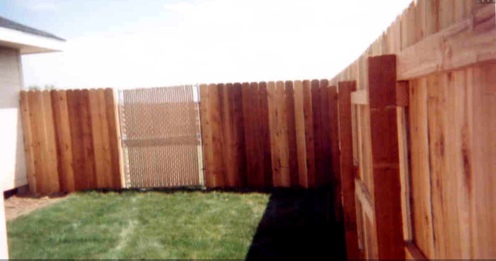 Classic wood privacy fence with chain link gate installed in a residential backyard