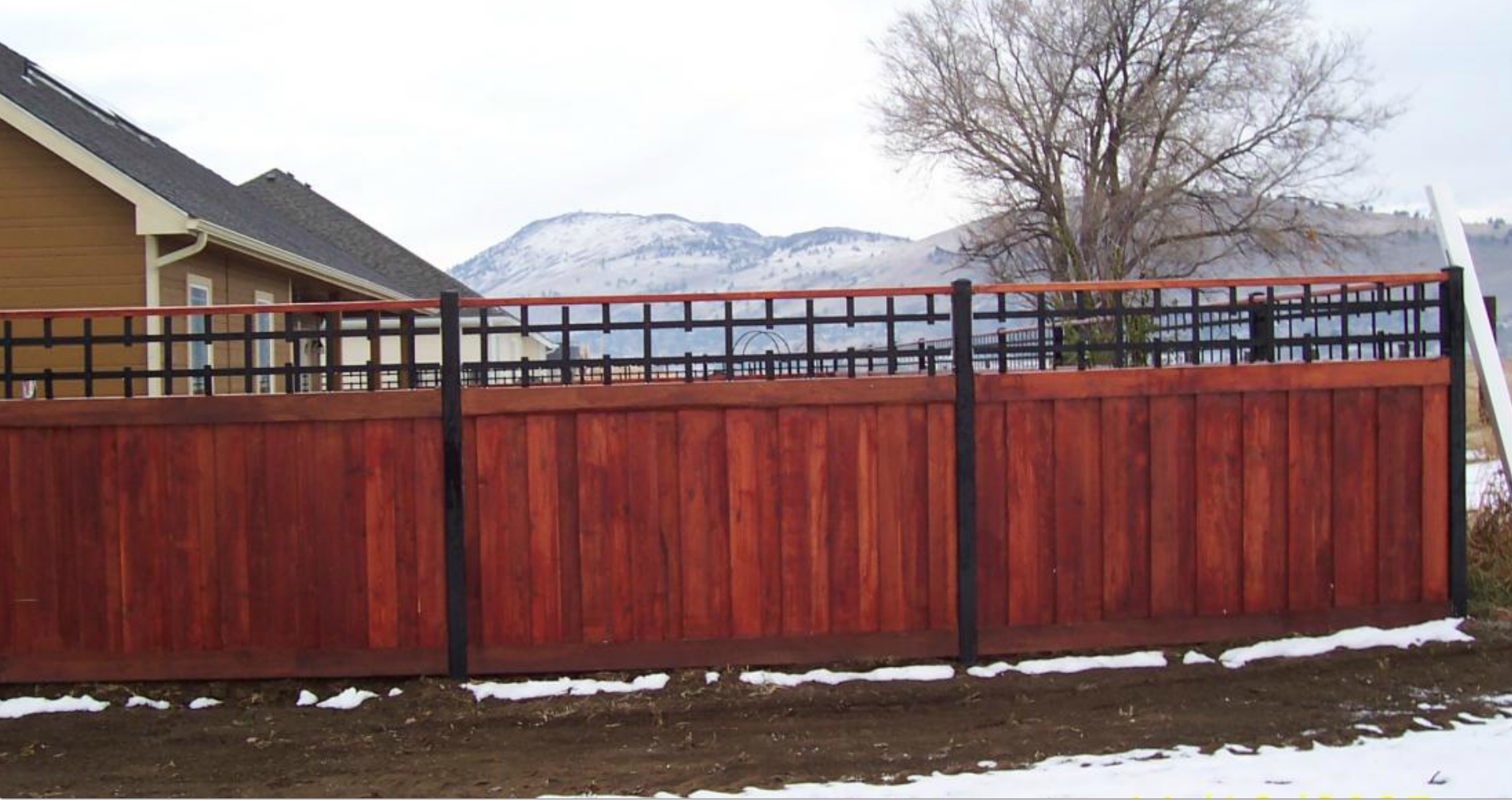Custom stained wood fence with ornamental iron top rail and mountain views